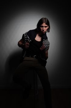 Striking low-key portrait of a young adult posing in dramatic studio lighting.