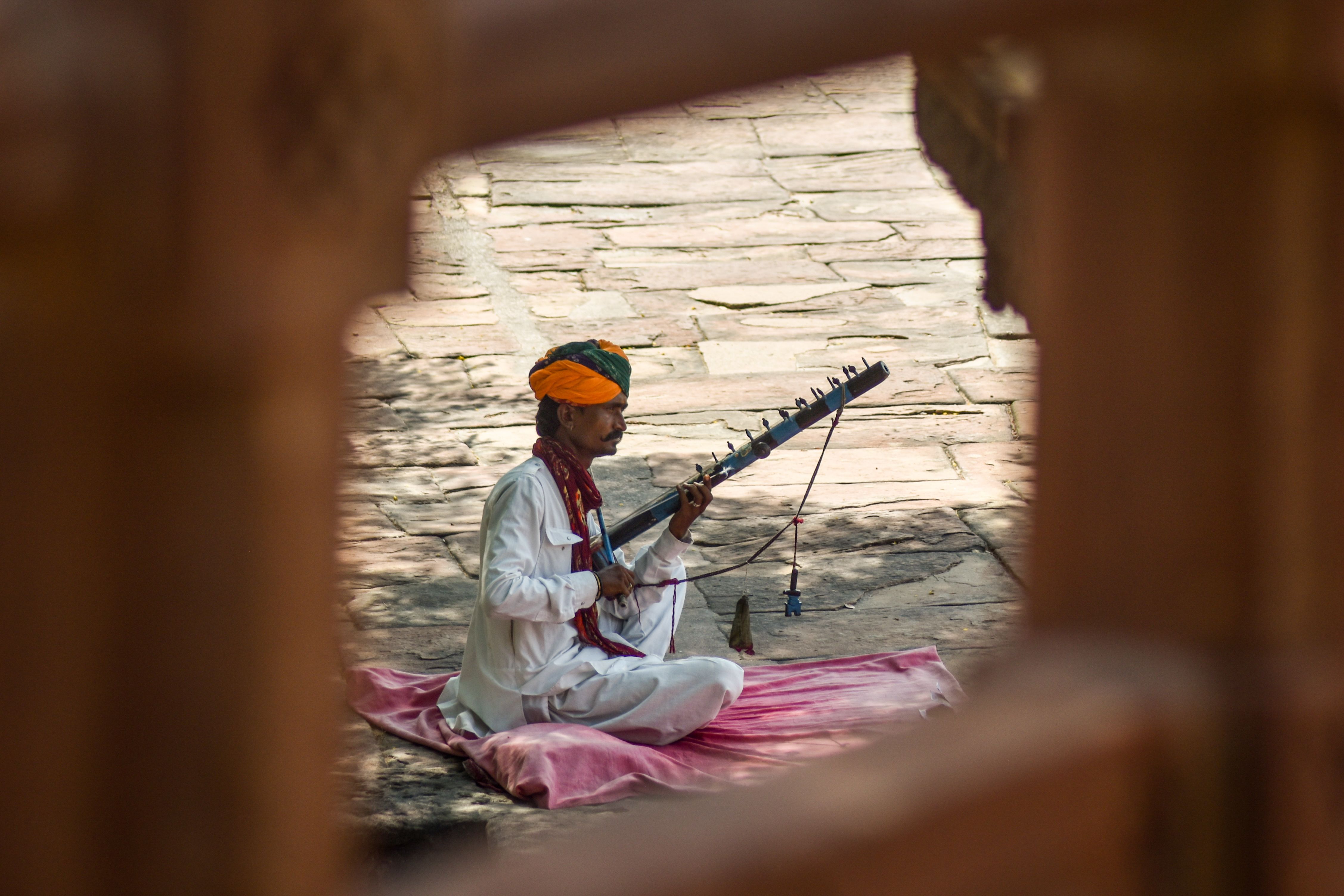 A Rajasthani musician performs outdoors with a traditional instrument in Jodhpur, India.