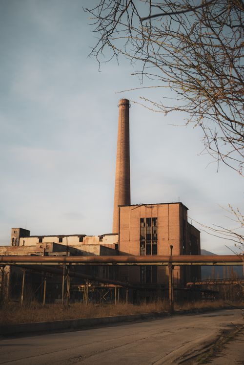 Free A deserted factory with a towering smokestack under clear skies, showcasing industrial decay. Stock Photo