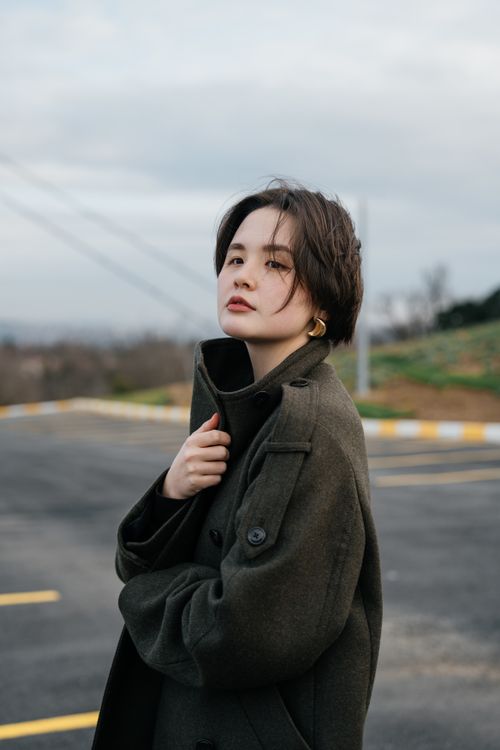 Woman in emerald green wool coat with black trousers