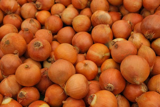 Close-up image of a large pile of fresh brown onions, perfect for culinary purposes.