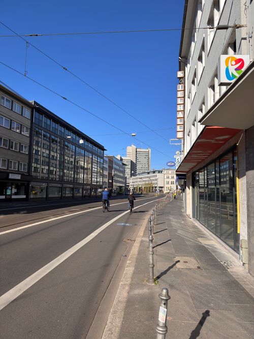 Free City street scene with cyclists, modern buildings, and a clear blue sky. Stock Photo