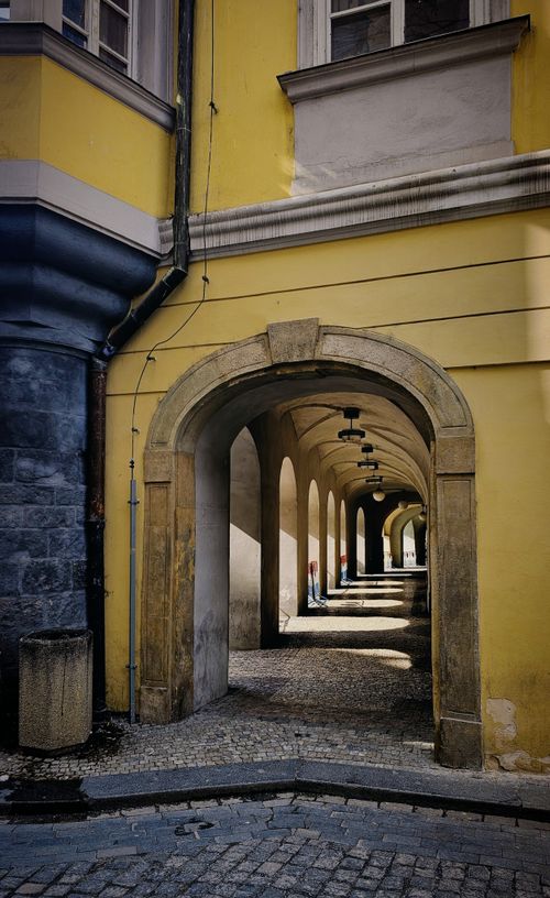 Free Elegant stone archway casting shadows in a historic European city street. Stock Photo