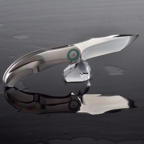 Free A sleek modern knife rests on water with a striking reflection, showcasing elegance and precision. Stock Photo