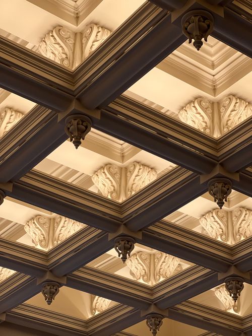 Free Elegant ceiling design featuring detailed plasterwork and decorative elements in a museum. Stock Photo