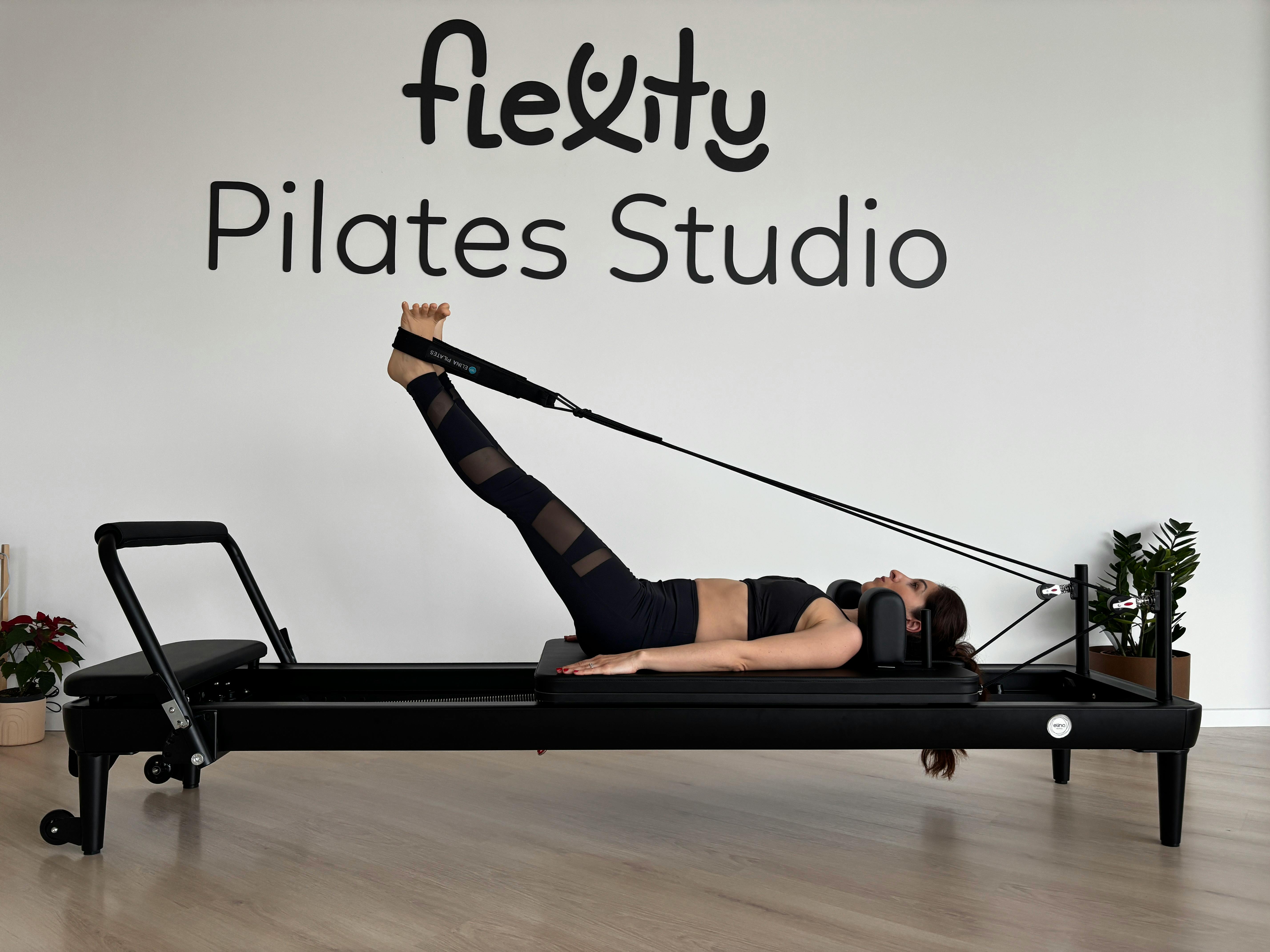 Woman performing pilates exercises on a reformer at Flexity Pilates Studio.