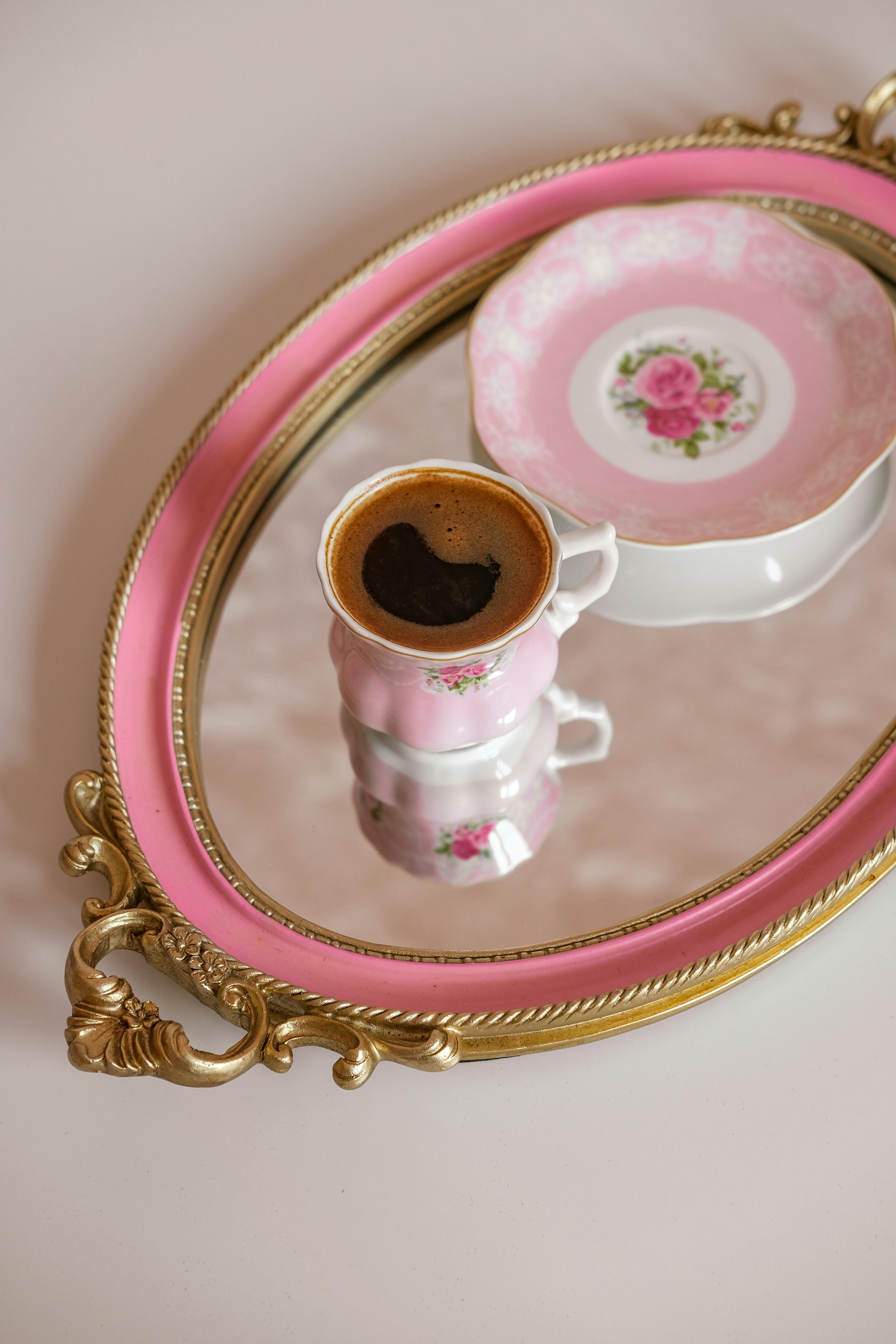 Turkish coffee in a floral cup on a mirrored tray, reflecting elegance.