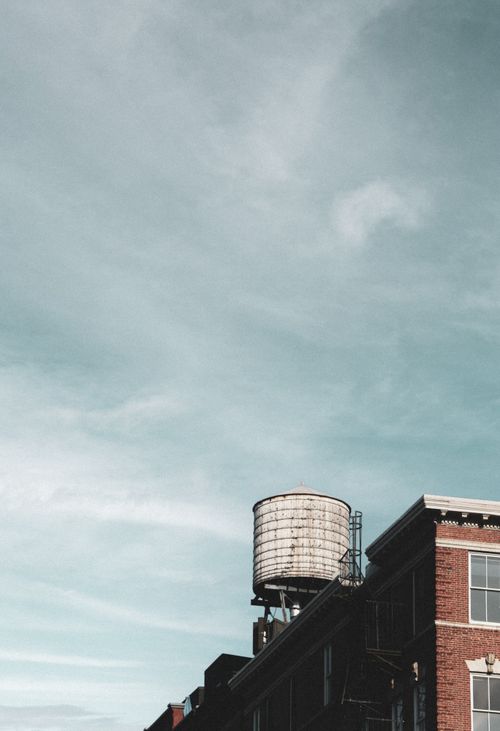 Free A classic water tower atop a historic building under a vast New York City sky. Stock Photo