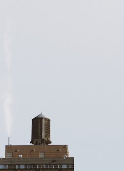 Minimalist photo of a classic New York water tower on a rooftop, highlighting architectural details against a clear sky.