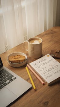 Warm and inviting scene with a book, coffee, and biscotti on a wooden table.