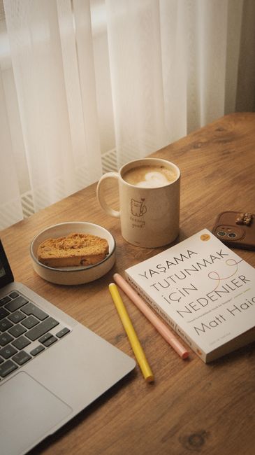Warm and inviting scene with a book, coffee, and biscotti on a wooden table.