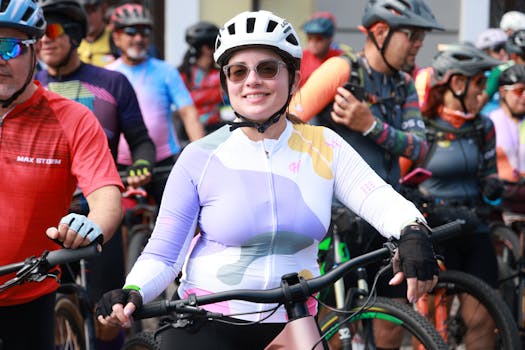 Smiling woman cyclist in colorful gear among a group of riders outdoors.