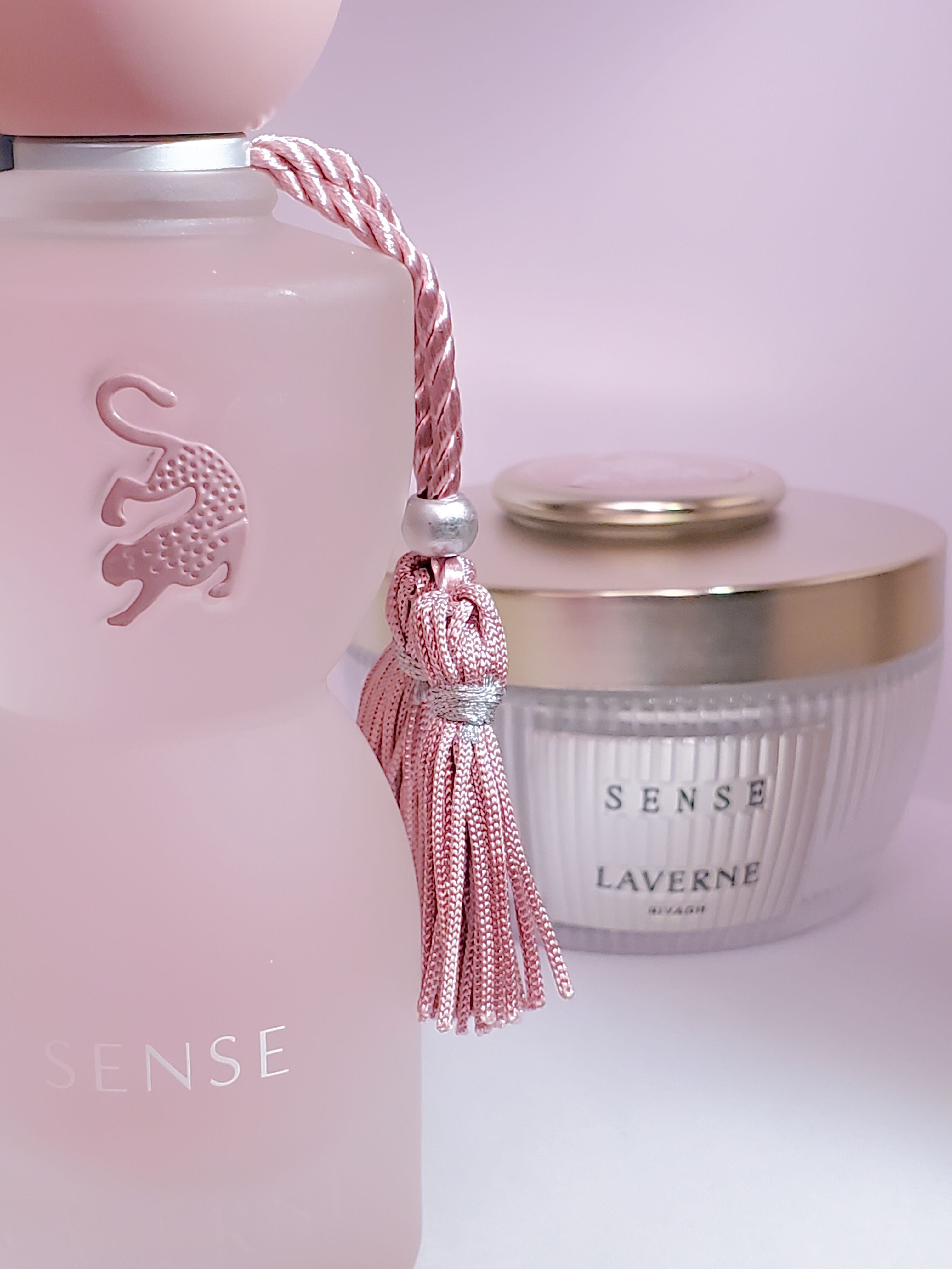 Stylish arrangement of a pink perfume bottle and a scented candle in soft lighting.