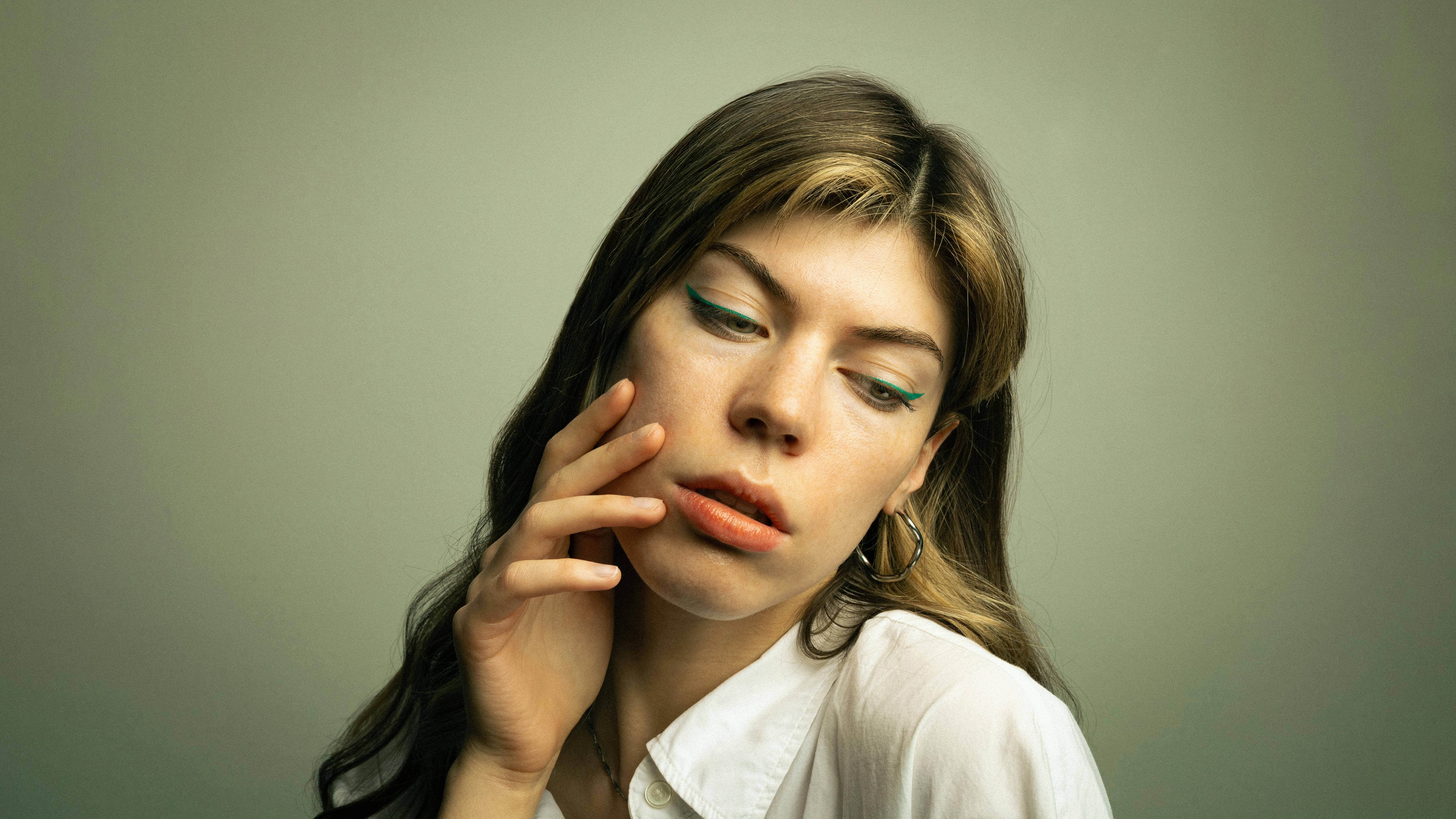 A thoughtful portrait of a woman with styled hair and colorful eyeliner, set in Berlin.