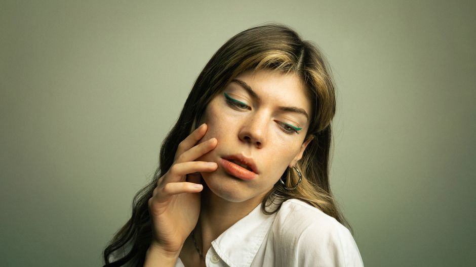 A thoughtful portrait of a woman with styled hair and colorful eyeliner, set in Berlin.