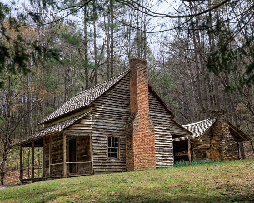 A historic wooden cabin in Cades Cove surrounded by green fields A historic wooden cabin in Cades Cove surrounded by green fields
