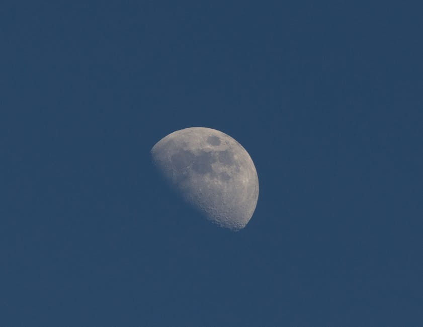 A sharp, detailed photo of a half moon against a deep blue sky taken in Jönköping, Sweden.