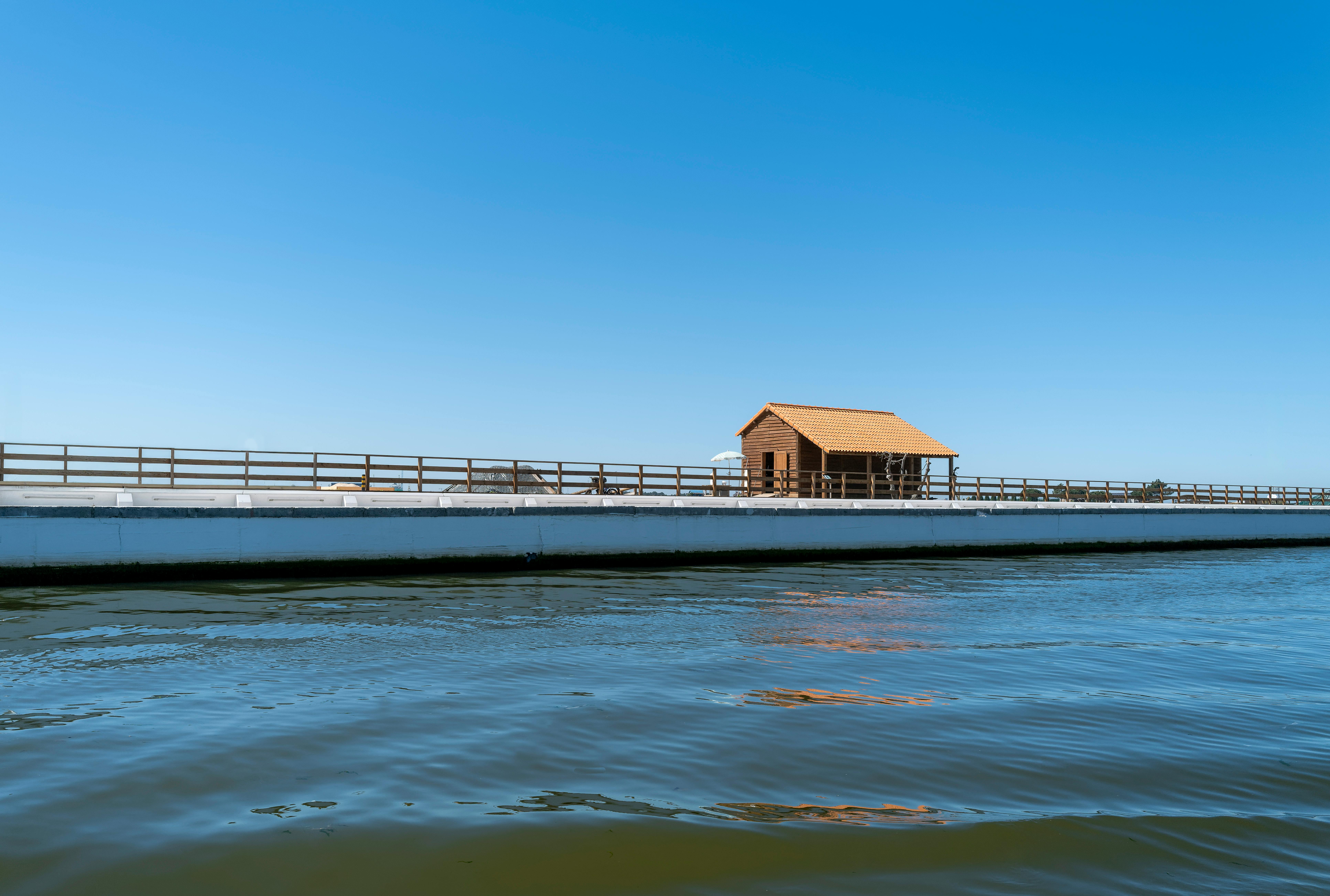 Discover a peaceful wooden hut along the serene waterfront of Aveiro, Portugal, on a clear summer day.