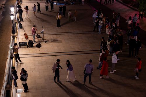 Free A lively night scene with a street performer and audience gathering on an outdoor promenade. Stock Photo
