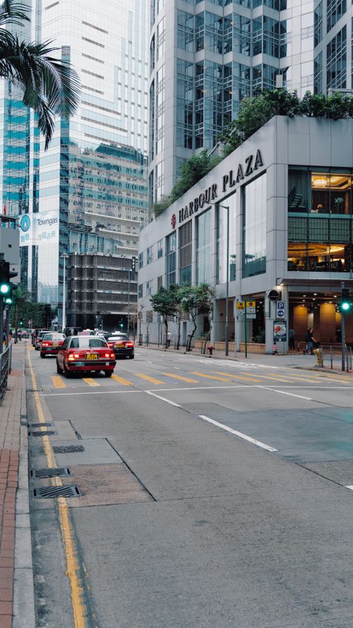 Free High-rise buildings and taxis on an urban street in Hong Kong's bustling cityscape. Stock Photo