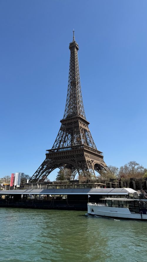 Free The iconic Eiffel Tower against a clear blue sky in Paris, viewed from the Seine River. Stock Photo