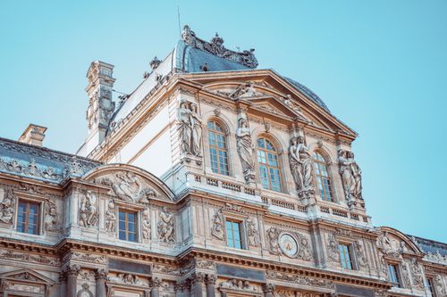 Free Intricate architectural details of the historic Louvre Museum under the clear Parisian sky. Stock Photo