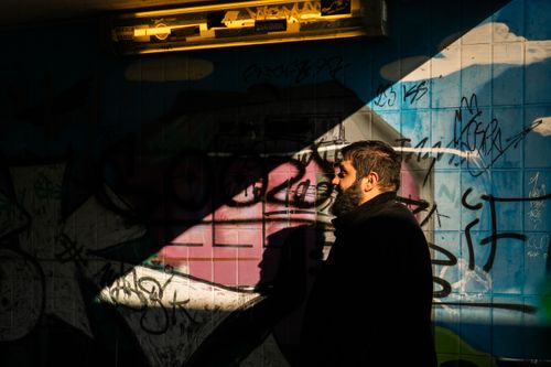 Free A man walks through a graffiti-covered tunnel in Kamen, Germany, highlighting dramatic shadows and urban art. Stock Photo