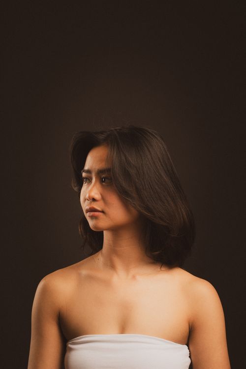 Free Stylish portrait of a woman with natural light and a dark background, emphasizing elegance and expression. Stock Photo
