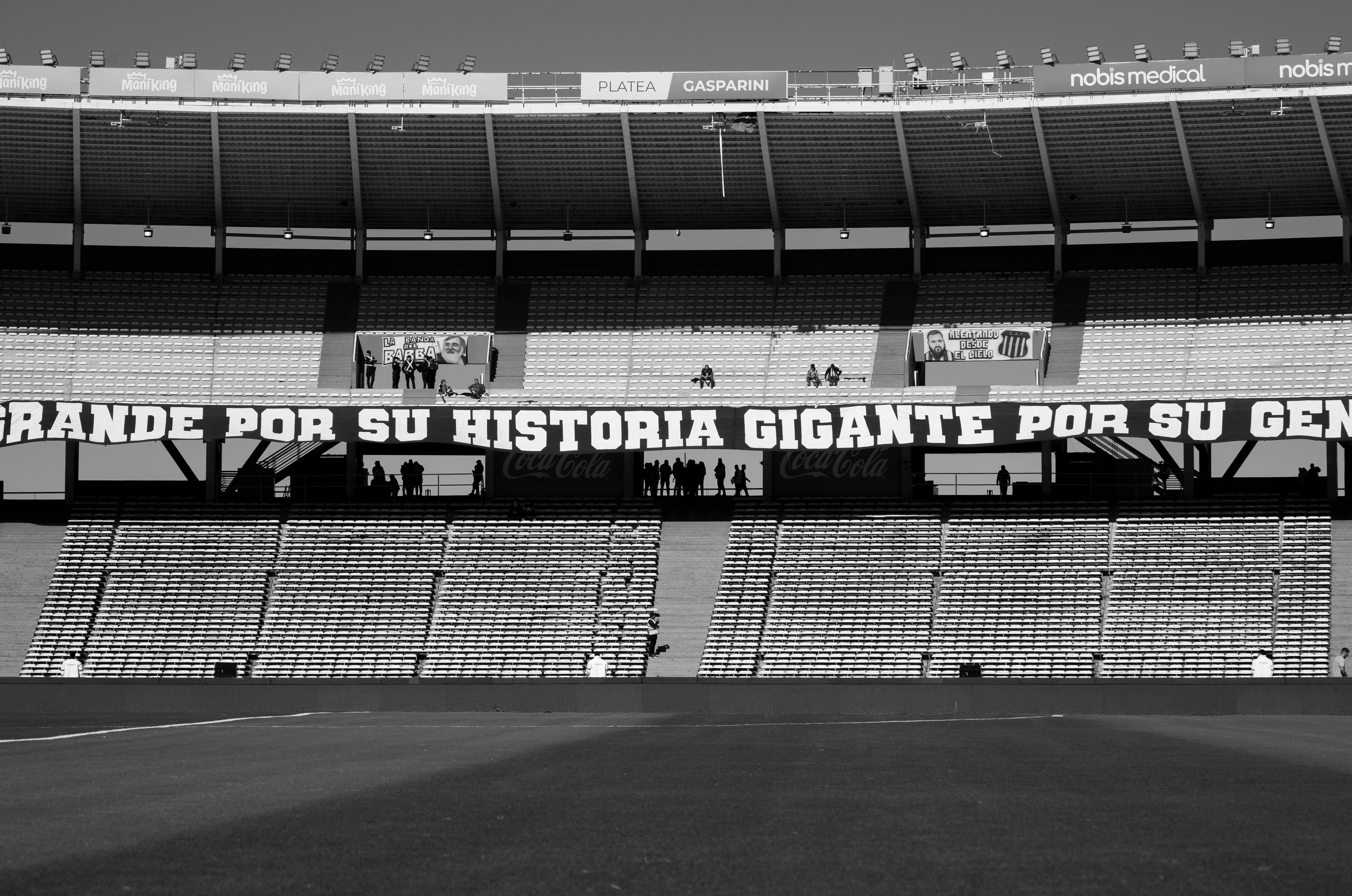 Monochrome view of a football stadium in Córdoba, Argentina, showcasing grandstands with iconic banners.