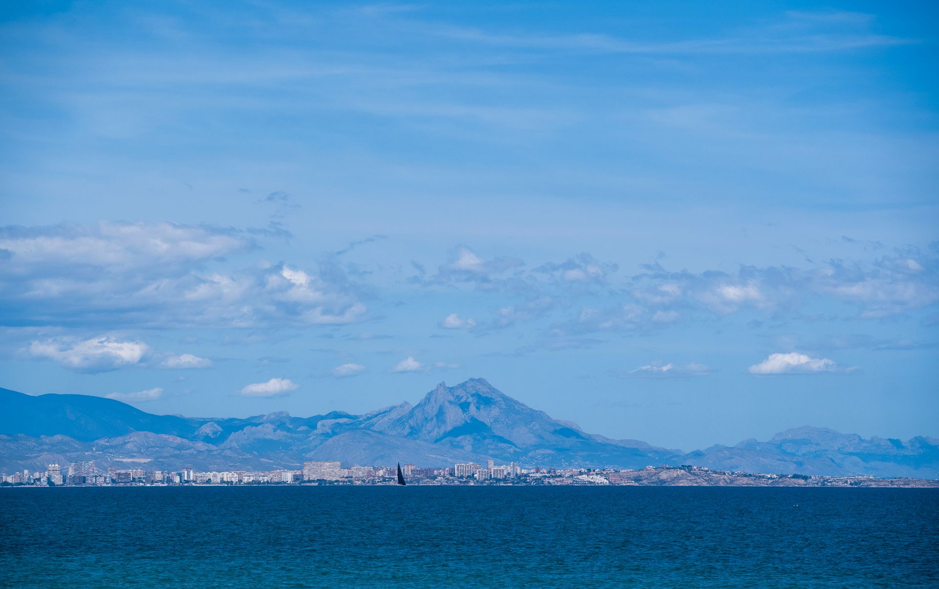 Scenic view of a coastal city with distant mountains under a clear blue sky.