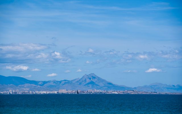 Scenic view of a coastal city with distant mountains under a clear blue sky.