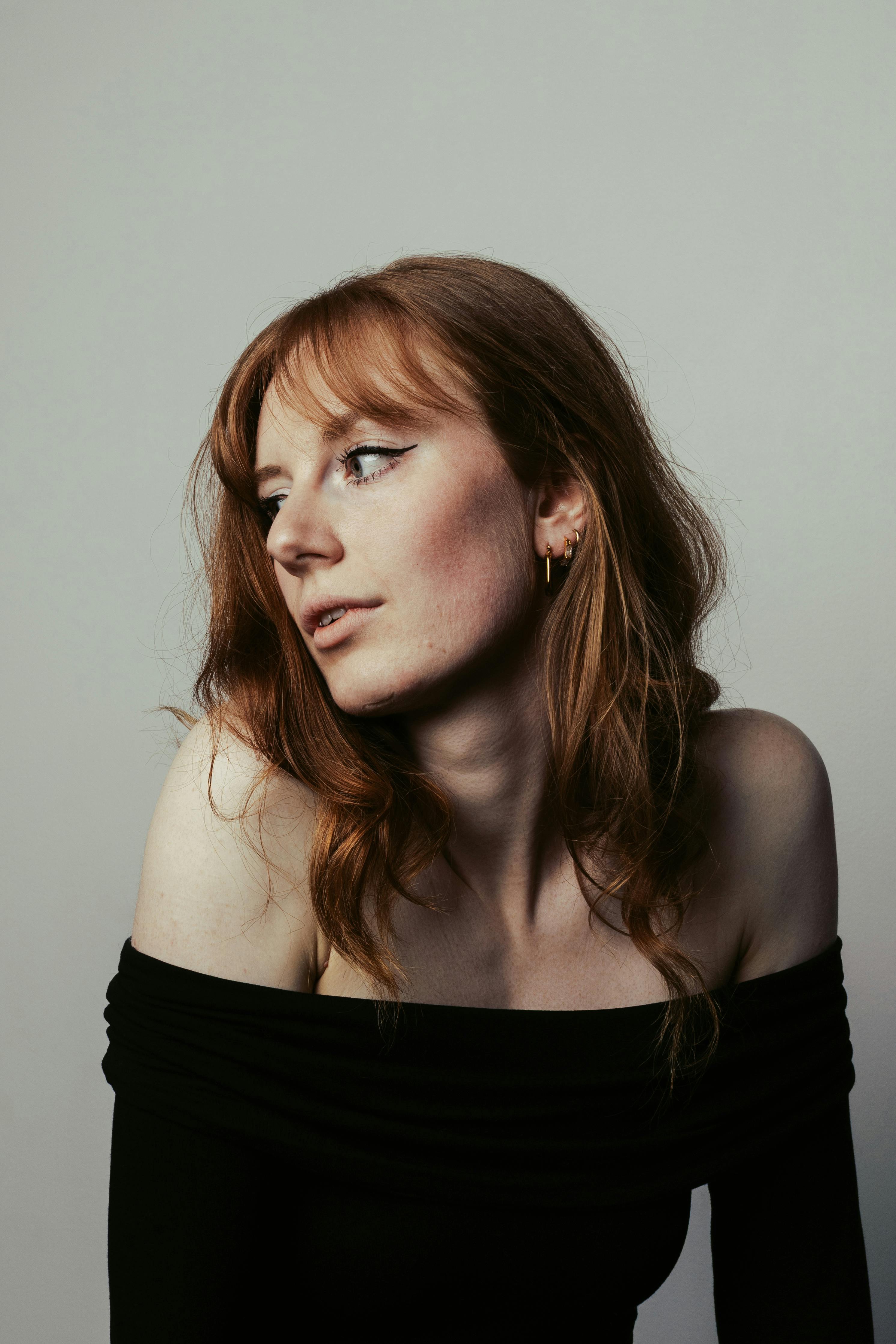 Classic portrait of a woman with red hair in an indoor studio setting, showcasing elegance and poise.