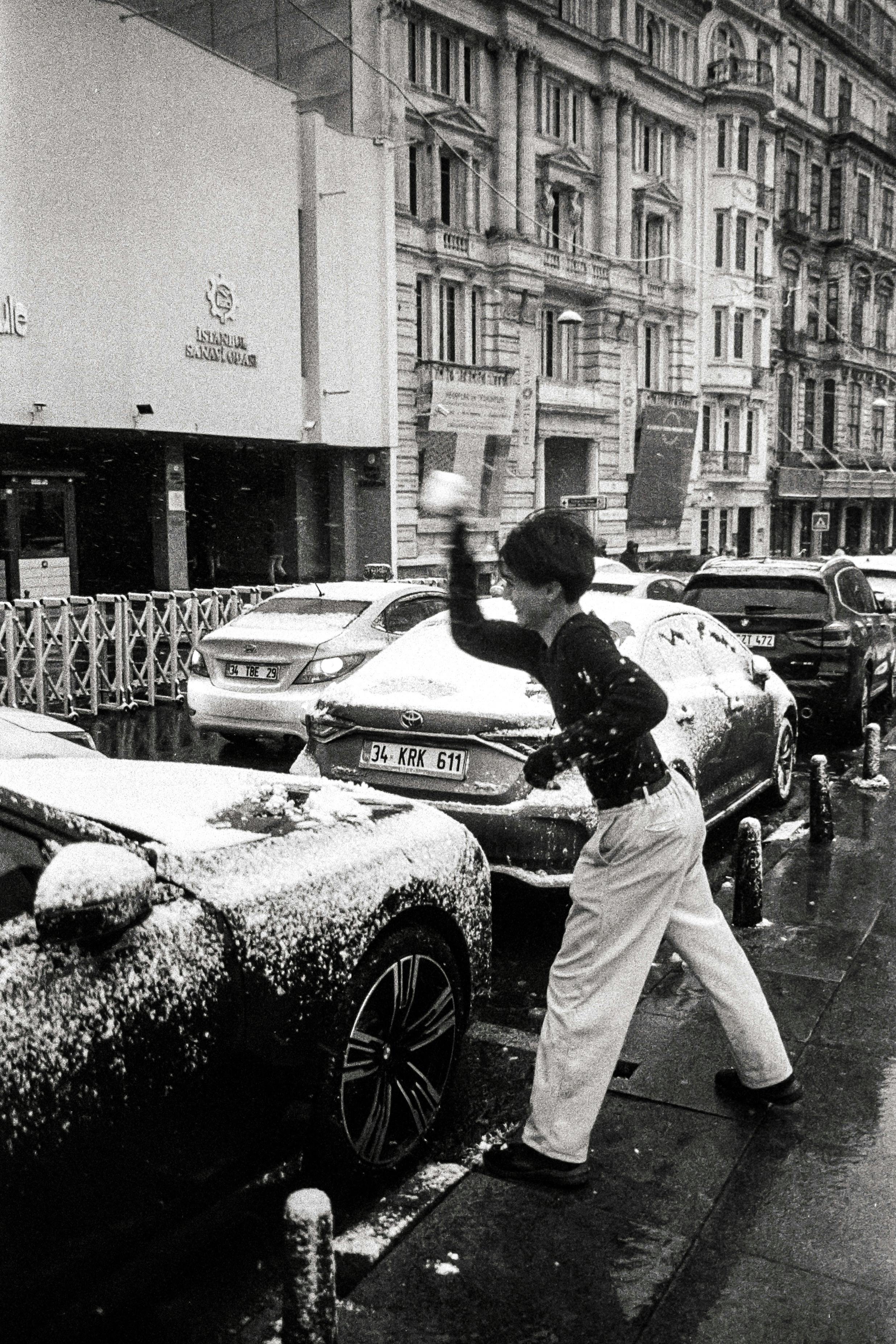 A person plays with snow on a city street in İstanbul, Türkiye.