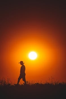 Beautiful silhouette of a person walking against a vibrant sunset sky.