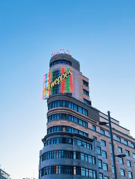 View of Capitol Building with Schweppes sign in Madrid under clear blue sky.
