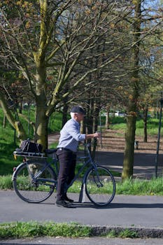 Elderly man with bicycle strolling through a sunlit spring park.
