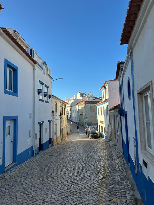 Free Charming cobblestone street with traditional architecture in Ericeira, Portugal under a clear blue sky. Stock Photo