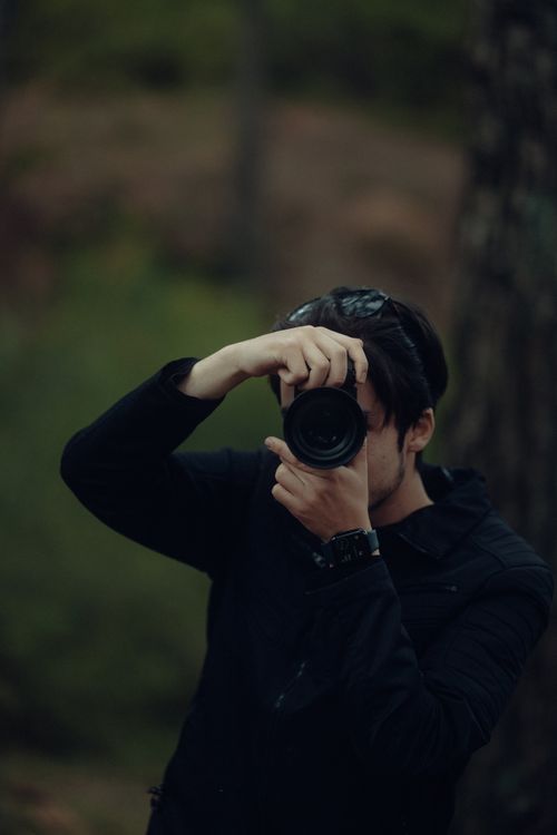 Free Portrait of a photographer taking pictures outdoors in a forest. Stock Photo