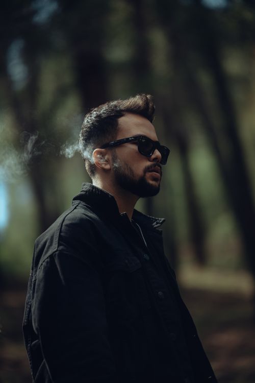 Free Profile of a man with sunglasses and smoke in a dark forest setting. Stock Photo