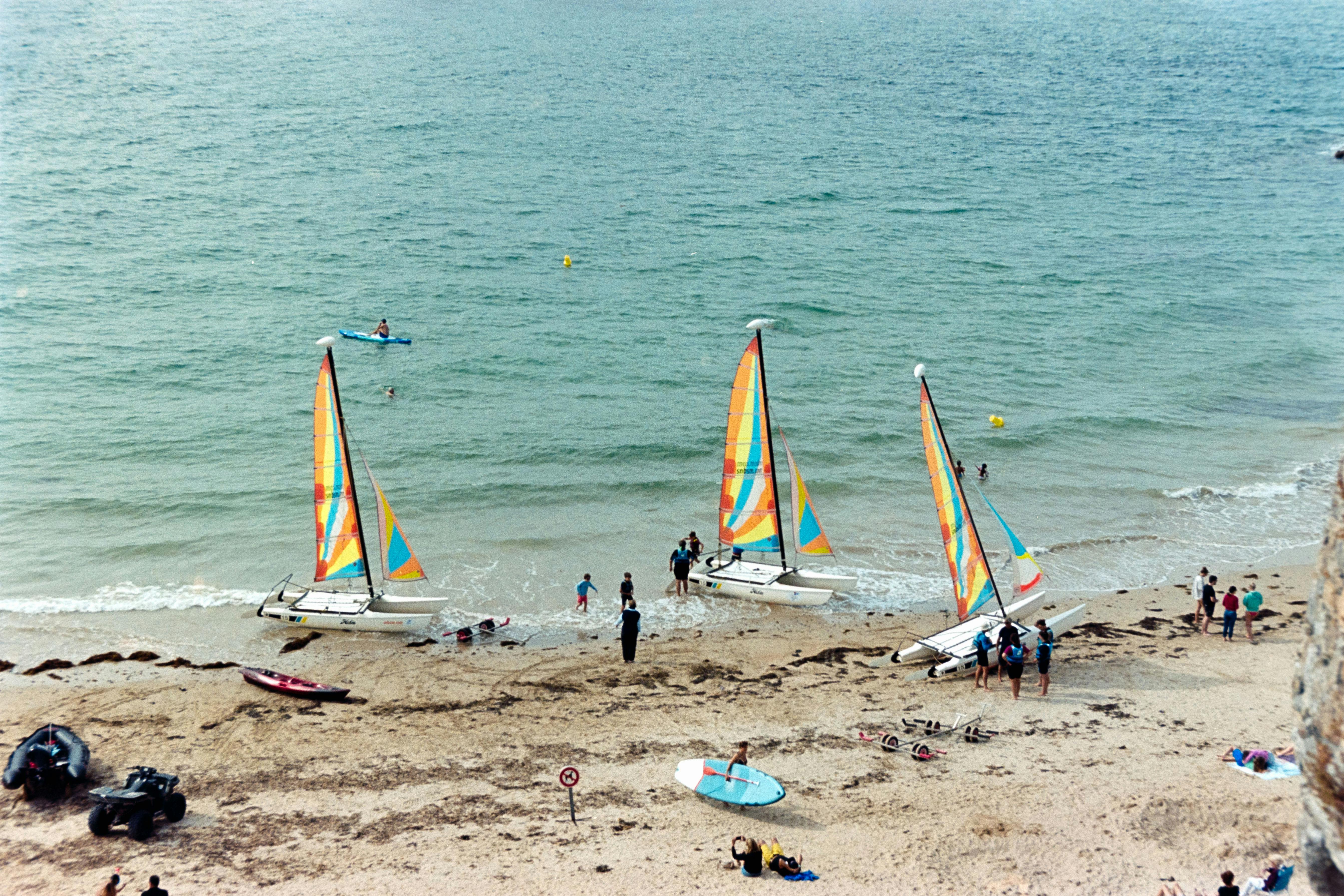 Vibrant sailboats and beachgoers enjoying a sunny day at Saint-Malo, France.