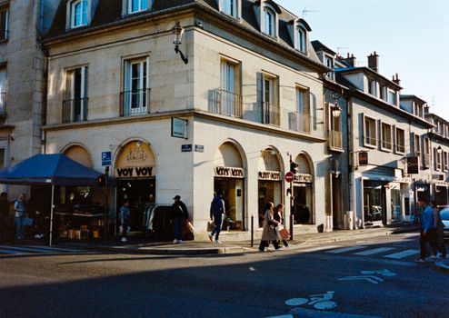 Street view of classic French architecture in Compiègne, capturing pedestrians on a sunny day.