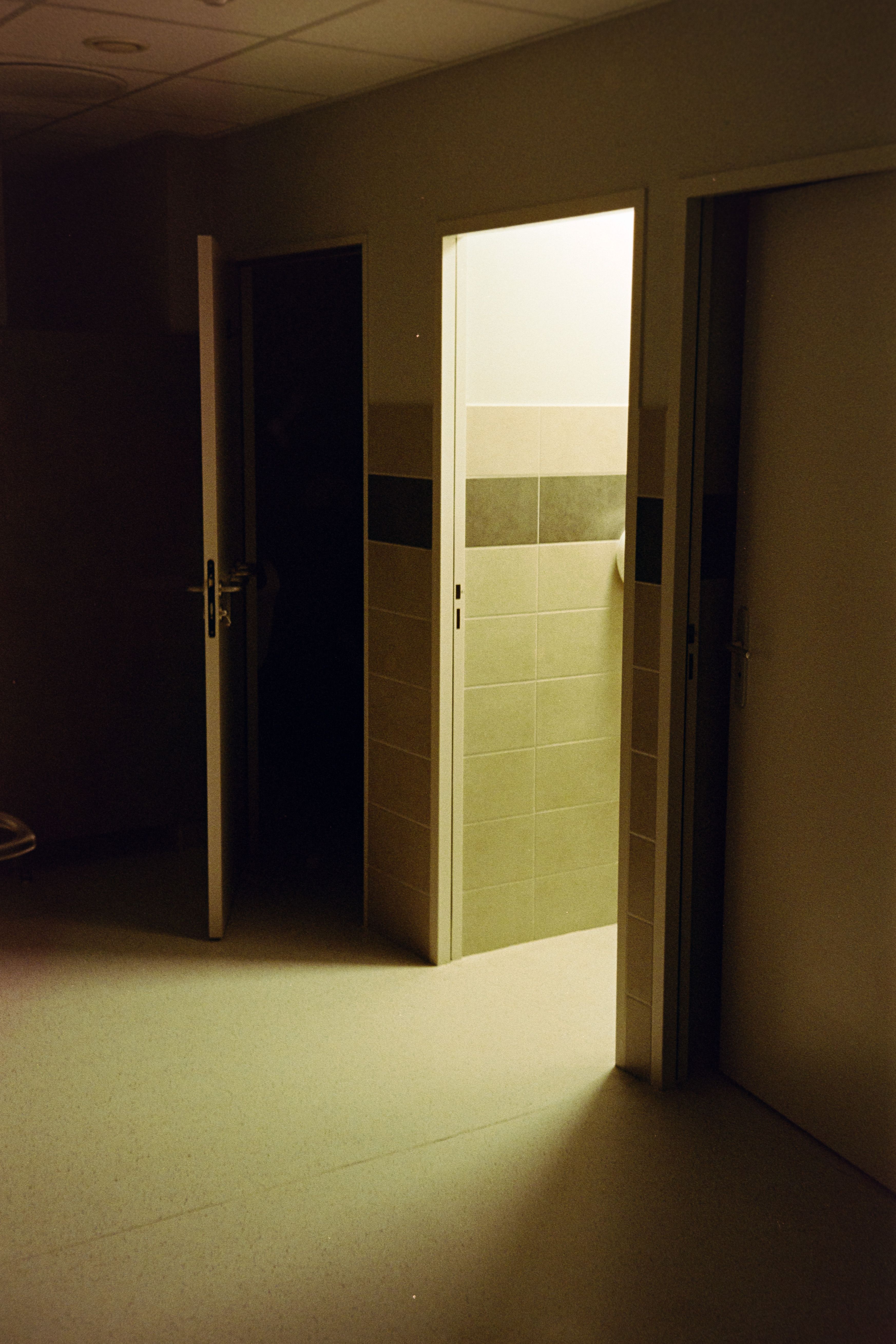 Three slightly open doors in a dimly lit hallway create an atmosphere of mystery and intrigue.