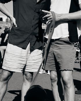 Close-up of two friends with a dog at an outdoor gathering, showcasing casual summer style.
