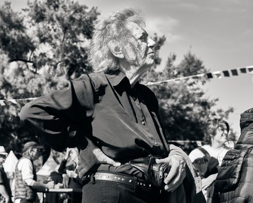 Free An elderly man gazing thoughtfully at an outdoor gathering in vintage black and white. Stock Photo
