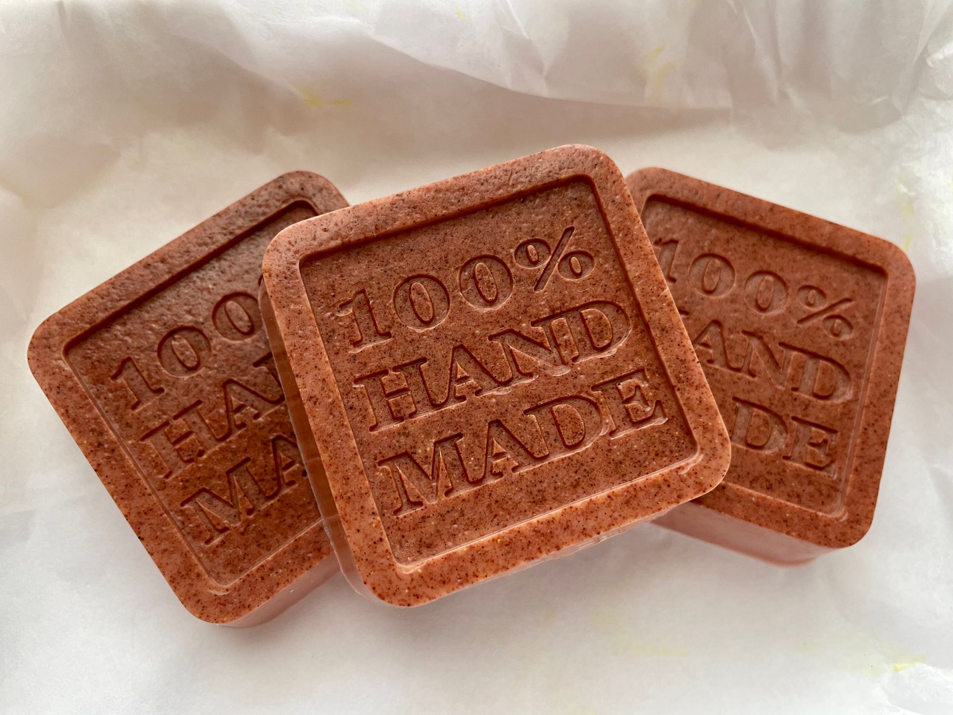 Close-up of natural, 100% handmade organic soap bars on white paper.