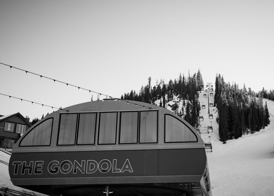 A monochrome image showing a gondola station at a snowy mountain resort.
