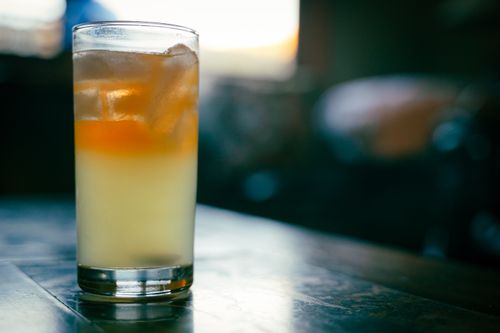 Free A glass of refreshing iced drink sits on a wooden table with a blurred background. Stock Photo