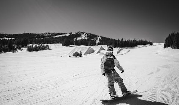 A snowboarder enjoying a sunny winter day on a snow-covered slope, captured in black and white.