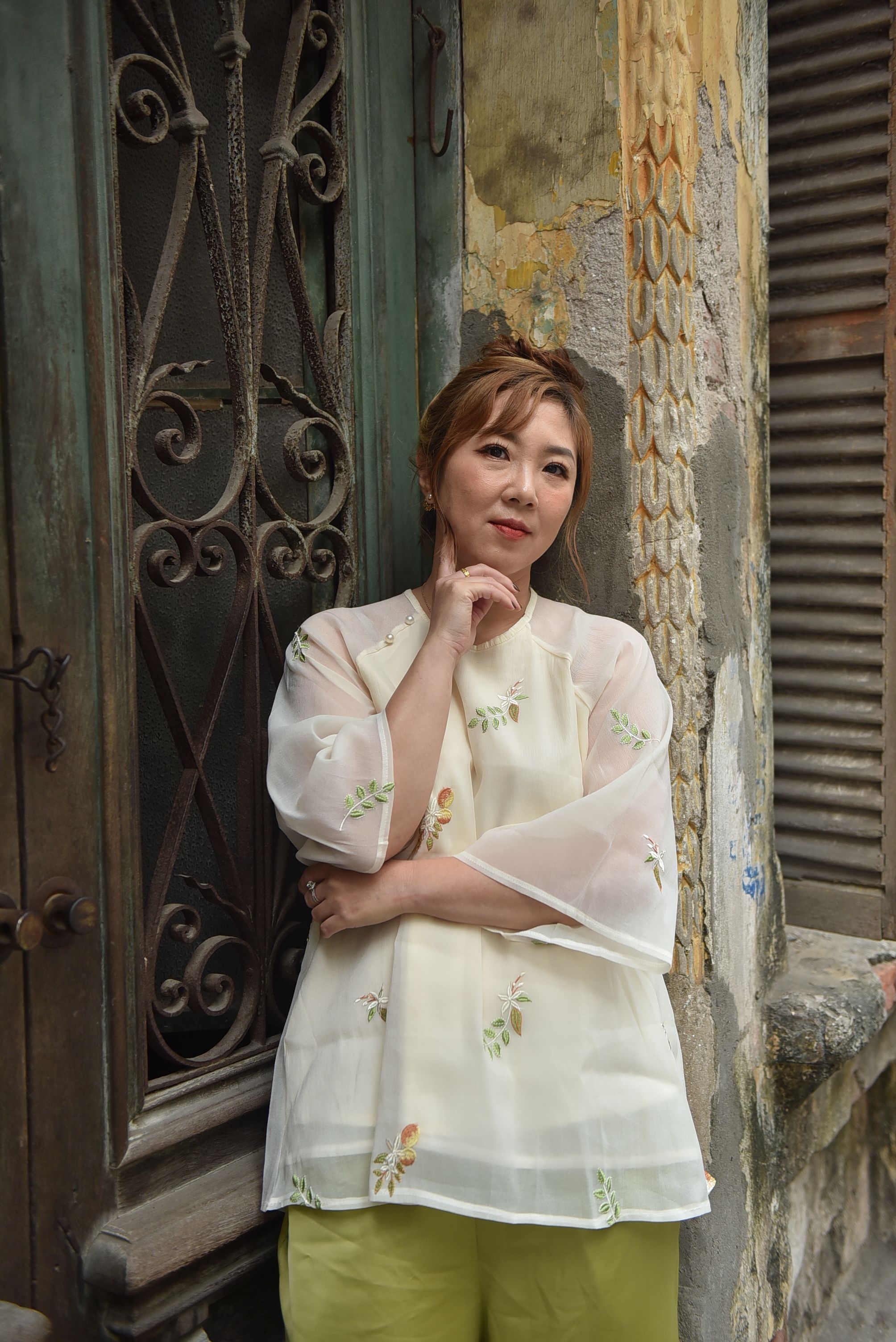 Thoughtful woman leaning against ornate door in urban environment.