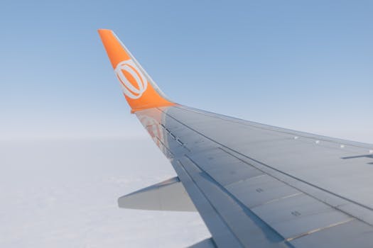 View of an airplane wing against a cloudy sky, showcasing modern aerial travel.